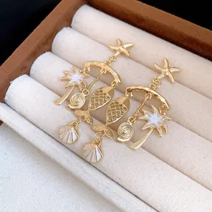 Detailed shot of gold-plated starfish, fish, and palm tree earrings in a jewelry box