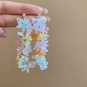 Dettaglio di orecchini colorati fatti a mano con perline e ciondoli a farfalla e fiore