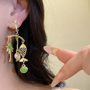 Detail view of gold ocean-themed earrings featuring starfish, fish, and shell charms.