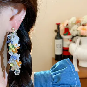 Primo piano di orecchini pendenti con perline di vetro colorate indossati da una modella