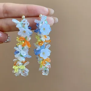 Primo piano di orecchini fatti a mano con perline di vetro colorate, perle e fiori