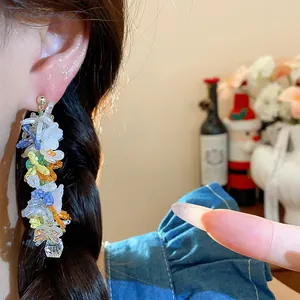 Dettaglio dell'orecchino pendente con perline di vetro a fiori e farfalle all'orecchio