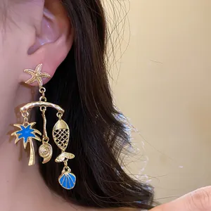 Detailed close-up of gold starfish and palm tree earrings with blue enamel accents