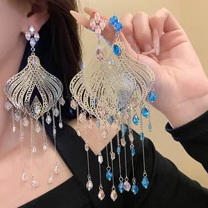 Close-up detail of ethnic vintage style silver needle glass teardrop tassel earrings on model