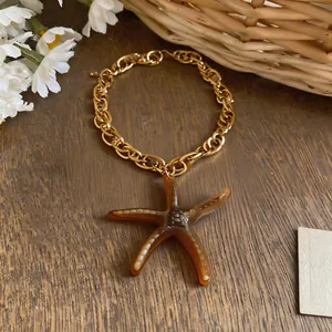 Gros plan détaillé d'un collier chaîne dorée avec un pendentif étoile de mer marron