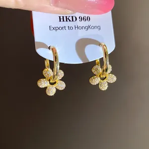 Gros plan détaillé de boucles d'oreilles créoles fleurs plaquées or 14k avec zircons