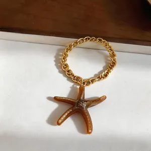Détail d'une breloque en chaîne dorée ornée d'un pendentif étoile de mer en résine