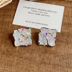 Close-up of irregular diamond stud earrings with colorful crushed ice texture