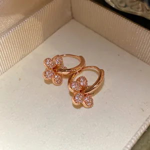 Gros plan de boucles d'oreilles créoles fleurs plaquées or 14 carats avec zircon.