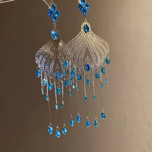 Detailed view of vintage silver needle earrings with blue glass water drop tassels