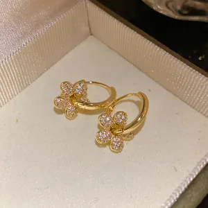 Détail rapproché élégant de boucles d'oreilles créoles fleurs en zircon plaqué or 14 carats en boîte
