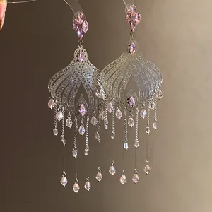Close-up of ethnic style tassel earrings with pink crystals and intricate silver filigree