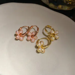 Gros plan de boucles d'oreilles fleurs plaquées or 14k avec zircons pavés