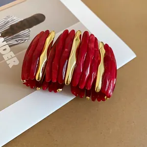 Bracciale rigido in acrilico marmorizzato rosso con raffinati accenti a onda dorati