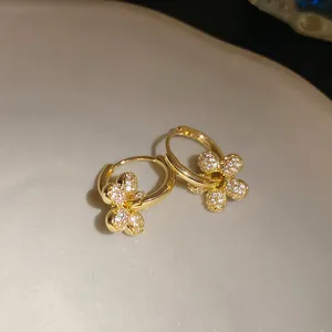Détail de boucles d'oreilles créoles fleurs plaquées or 14 carats avec zircons