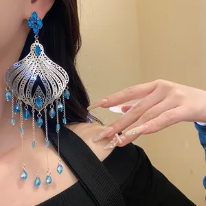 Detailed view of ethnic vintage tassel earrings with blue glass teardrops worn by model.