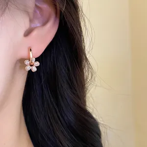 Vue détaillée d'élégantes boucles d'oreilles pendantes fleurs en plaqué or et zircon