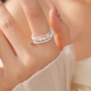 Elegant multi-layer silver ring featuring a delicate pearl strand and stylish twisted bands