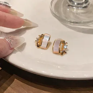 Detailed view of elegant gold-toned earrings with iridescent pearl inlay and zircon