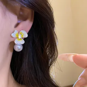 Detailed close-up view of silver needle earring with enamel flower and pearl pendant