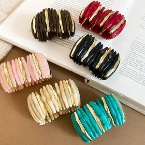 Primo piano di braccialetti elastici in acrilico marmorizzato e metallo dorato in vari colori