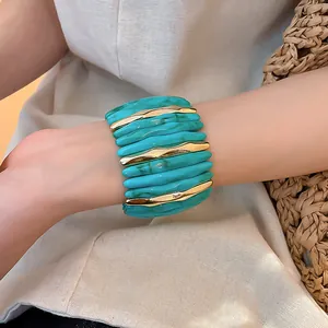 Dettaglio del bracciale in acrilico marmorizzato turchese con segmenti dorati