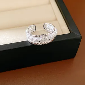 Detailed view of an elegant multi-layer silver ring with white pearls and zircons