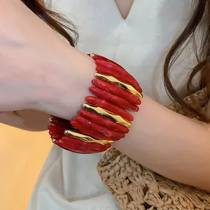 Dettaglio ravvicinato di un bracciale in acrilico marmorizzato rosso e metallo dorato
