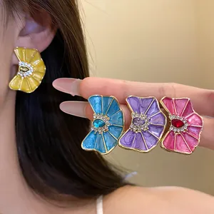 Detalle de pendientes de flores en esmalte de colores con centro de pedrería fina