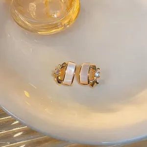 Close-up of elegant gold fleur-de-lis earrings with mother-of-pearl and zircon