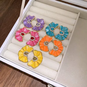 Variedad de pendientes de botón de esmalte de colores con forma de flor en un joyero blanco