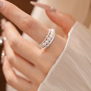 Detailed close-up of a multi-layer silver ring with pearls and pavé zircon on a finger