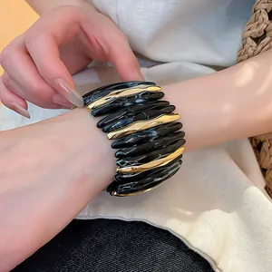 Dettaglio di un lussuoso bracciale in acrilico marmorizzato con accenti metallici dorati al polso