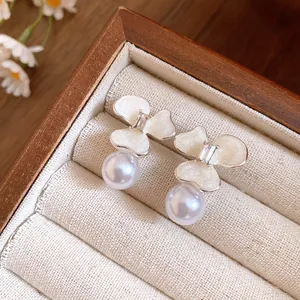 Close-up of elegant flower stud earrings with white pearls in a wooden jewelry box display