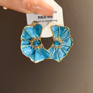 Vista detallada de pendientes de flores plisadas en esmalte azul