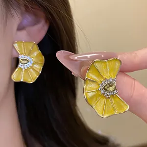 Vista detallada de pendientes de flor de esmalte amarillo con cristales y pétalos