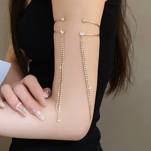 Dettaglio di bracciale da braccio dorato a doppio strato con nappe lucenti di strass