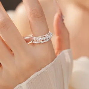 Detail view of an elegant multi-layer silver ring set with white pearls and textured bands