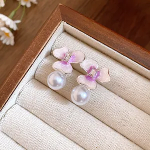 Detailed macro close-up of silver flower pearl earrings with pink enamel finish