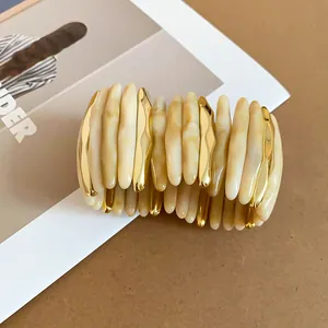 Dettaglio di un bracciale largo con segmenti in acrilico marmorizzato e metallo oro