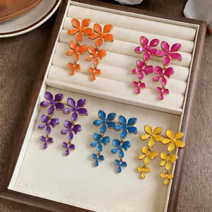 Colorful enamel flower tassel earrings collection displayed in a cream jewelry tray