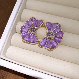 Primer plano de elegantes pendientes de flores de esmalte plisado morado con cristal