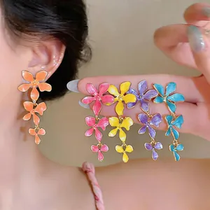 Close-up of colorful floral tassel earrings featuring enamel petals and silver needles