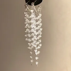 Detail of silver needle drop earrings with sparkling crystal tassels and multiple chains.