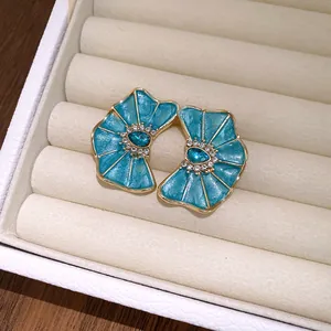 Primer plano de pendientes de flor de esmalte azul con diamantes en un joyero