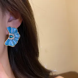 Primer plano de pendientes de flor en esmalte azul con brillantes en una modelo