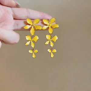 Close-up detail of elegant yellow enamel triple flower tassel earrings for women