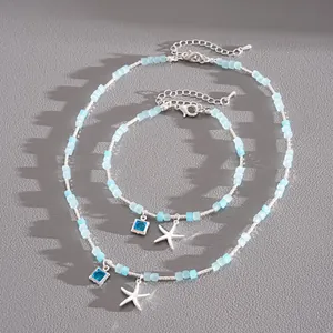 Détail d'un ensemble collier et bracelet en perles de verre bleu clair avec étoiles de mer.