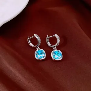 Détail de boucles d'oreilles en argent avec zircons carrés bleus et anneaux pavés