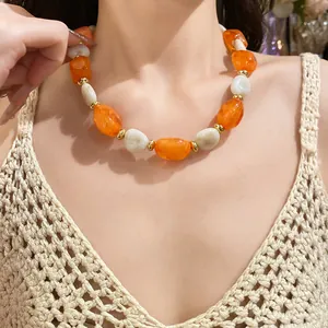Close-up of vintage orange and white acrylic oval bead necklace worn on neck.